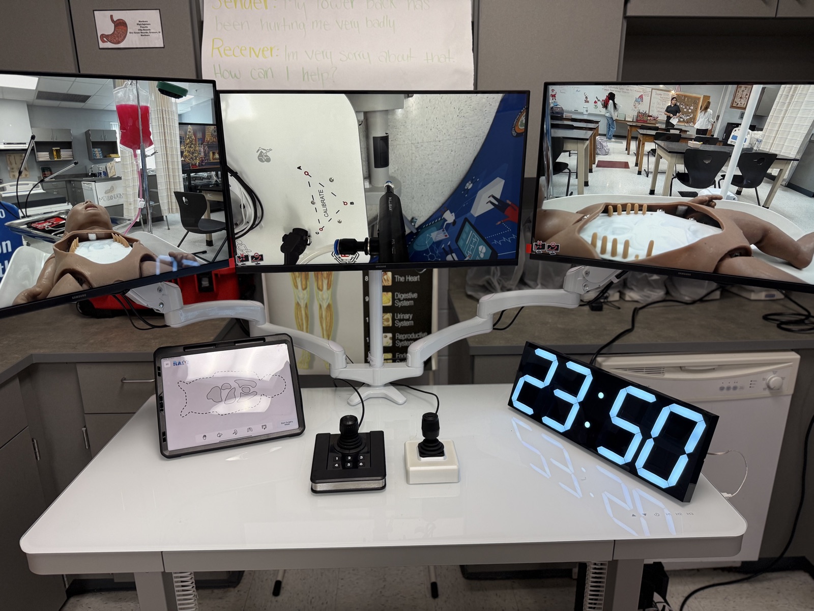 CARE medical robotics simulation console with three camera views, tablet controls, and training mannequin